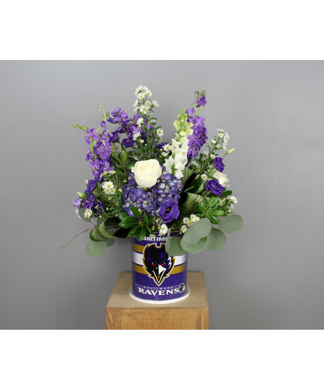 A festive purple and white Baltimore Ravens arrangement designed in a reusable tin container.