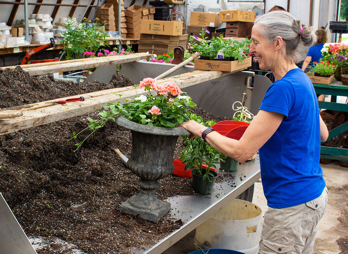 A smiling Radebaugh employee pots a plant in our designers' workroom